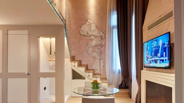 A modern living room with a glass table, a decorative wall piece, a television, and a staircase. - Ca' Dei Proverbi Suites - Wenice Deep Culture (Venice)