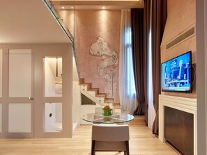 A modern living room with a glass table, a decorative wall piece, a television, and a staircase. - Ca' Dei Proverbi Suites - Wenice Deep Culture (Venice)