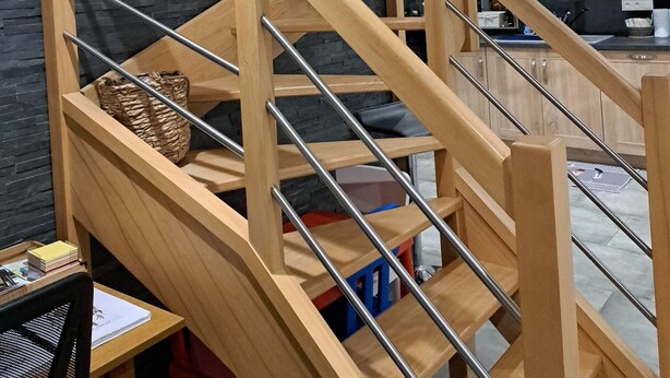 Een modern interieur met een houten trap, een zwarte muur en een keukenhoek.