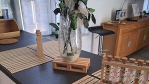 Een moderne keuken met een houten tafel, een vaas met gedroogde takken en een houten kast.