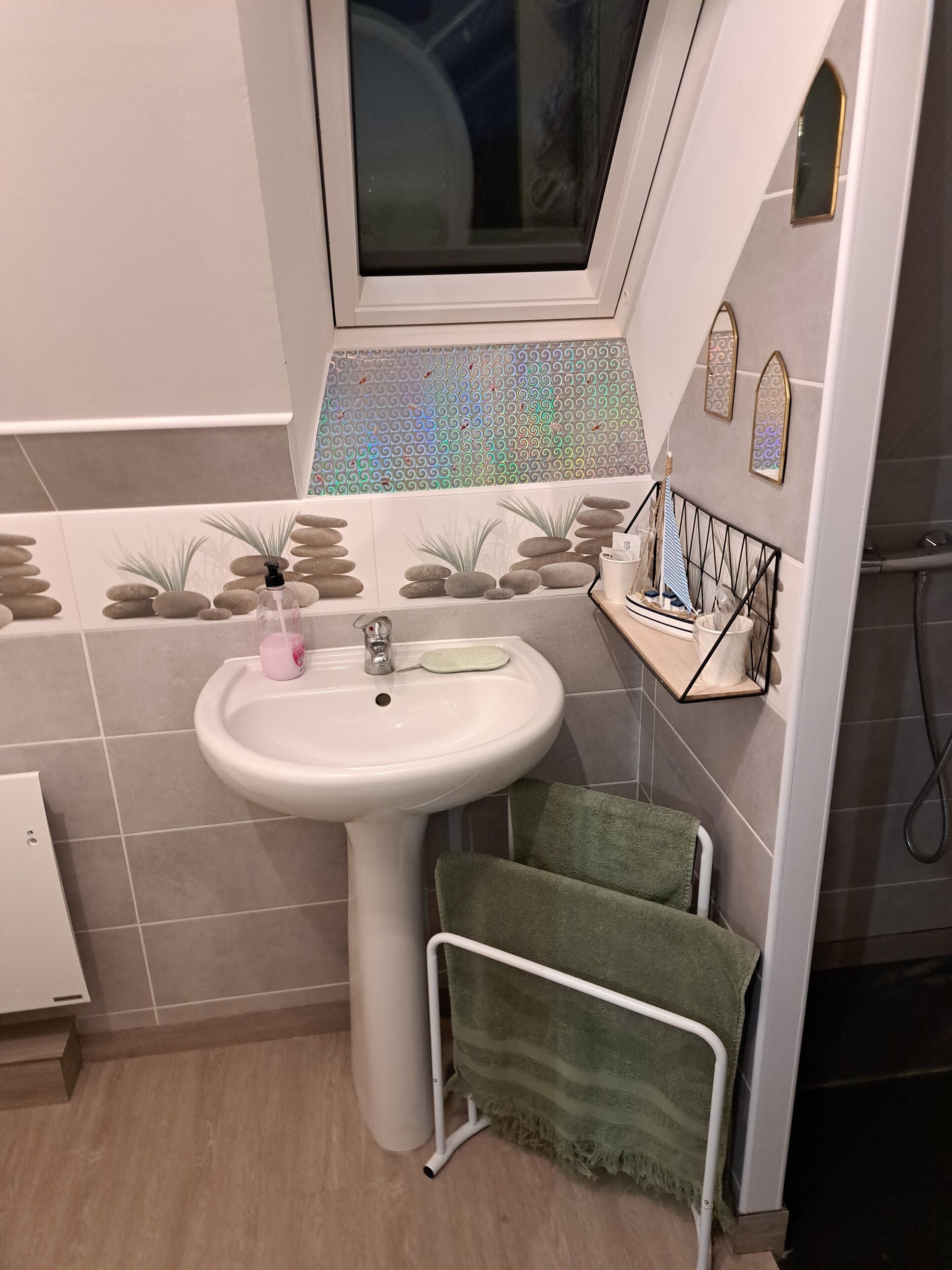 A bathroom with a sink, a window, and a towel rack.