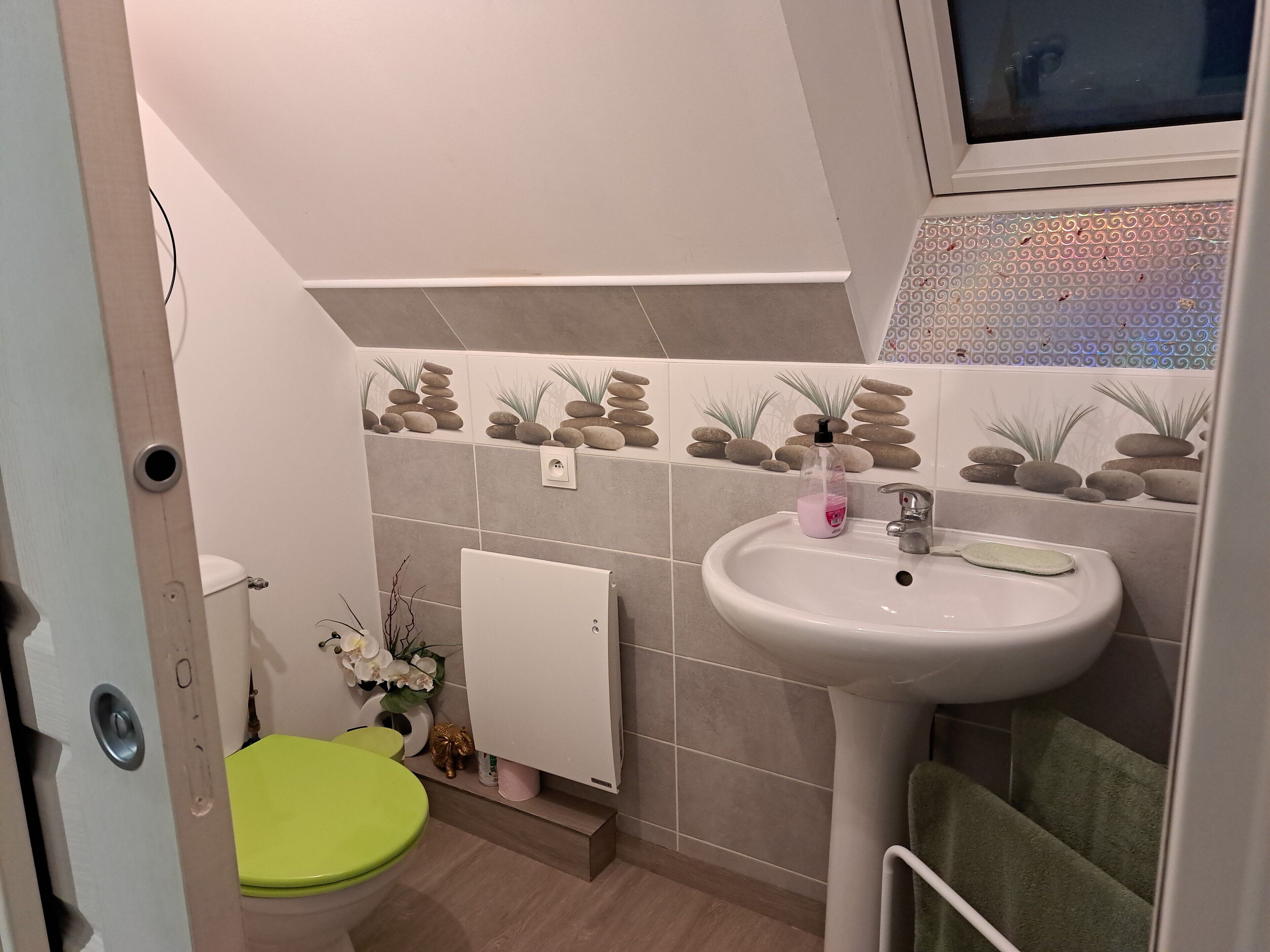 A bathroom with a toilet, sink, and decorative tiles.