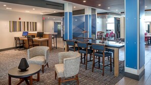 A hotel lobby with a reception desk, seating area, and a bar. - Holiday Inn Express & Suites West Omaha - Elkhorn by IHG (Elkhorn)