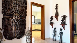 A hallway with a large wooden carving, a small metal sculpture, and several small statues on shelves. - Villa Timanfaya Private Pool By PVL (Yaiza)