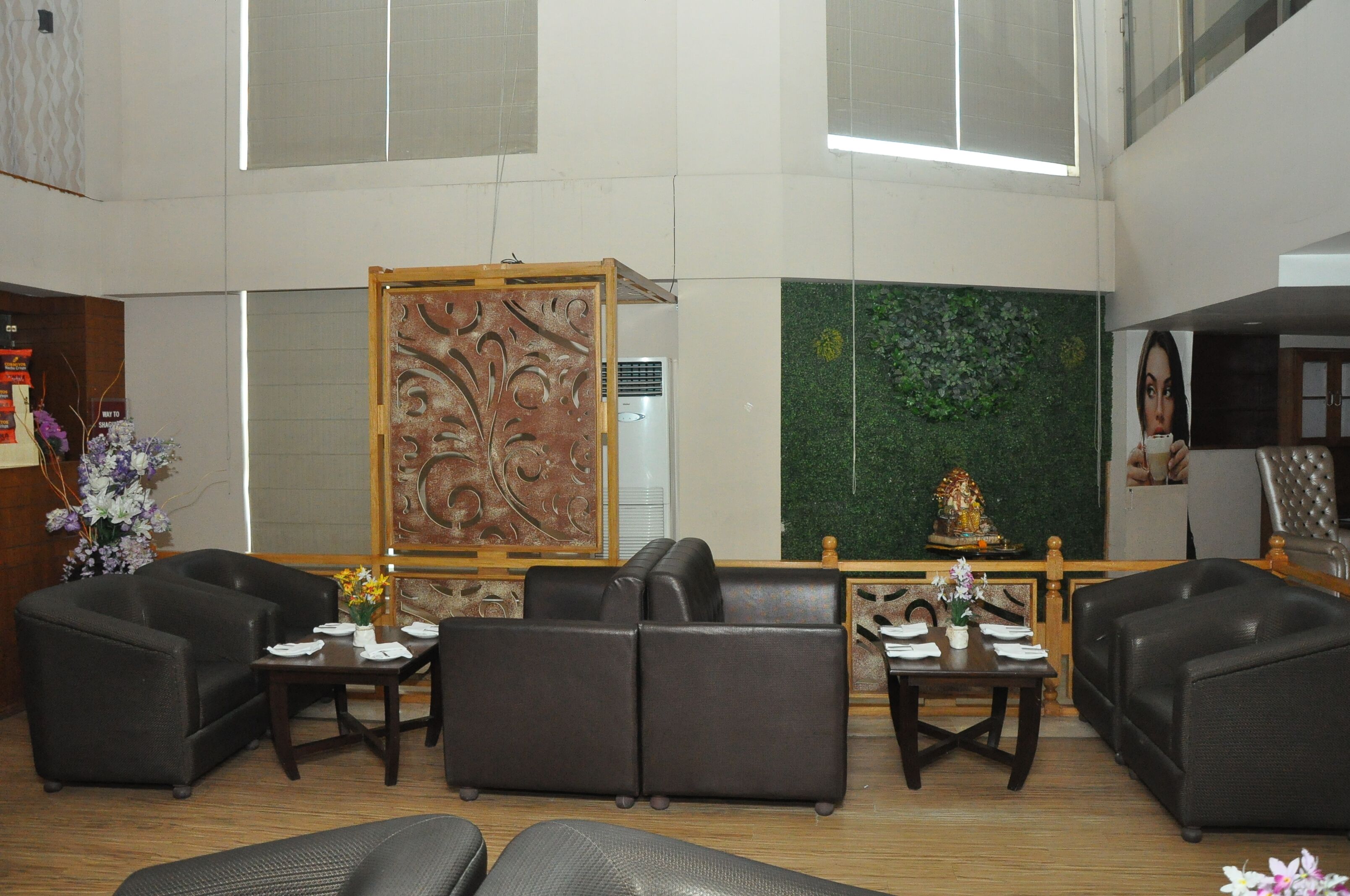 A lobby with leather sofas, a reception desk, a decorative panel, and a green wall with a statue.
