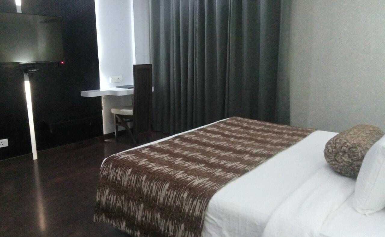 A hotel room with a bed, a desk, and a chair.