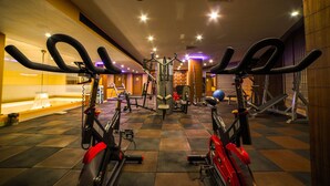 Een sportschool met hometrainers, loopbanden en diverse fitnessapparaten.