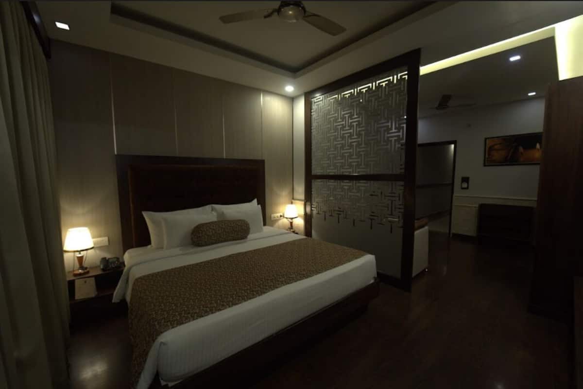 A hotel room with a large bed, two bedside lamps, a ceiling fan, and a decorative wall panel.