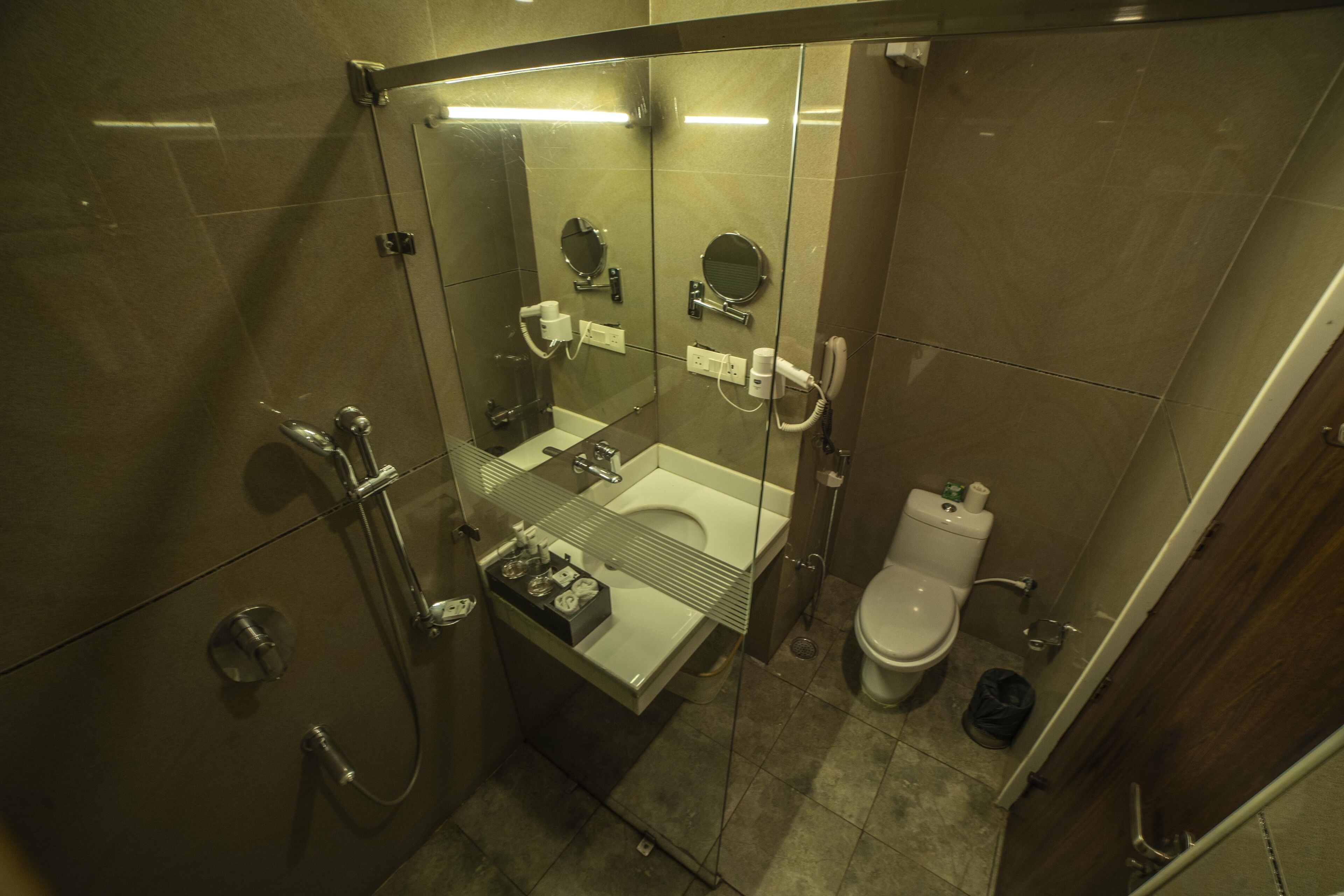 Uma casa de banho moderna com chuveiro de vidro, lavatório com espelho e sanita.