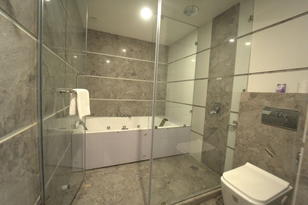 A modern bathroom with a glass-enclosed shower, a freestanding bathtub, and a separate toilet area.