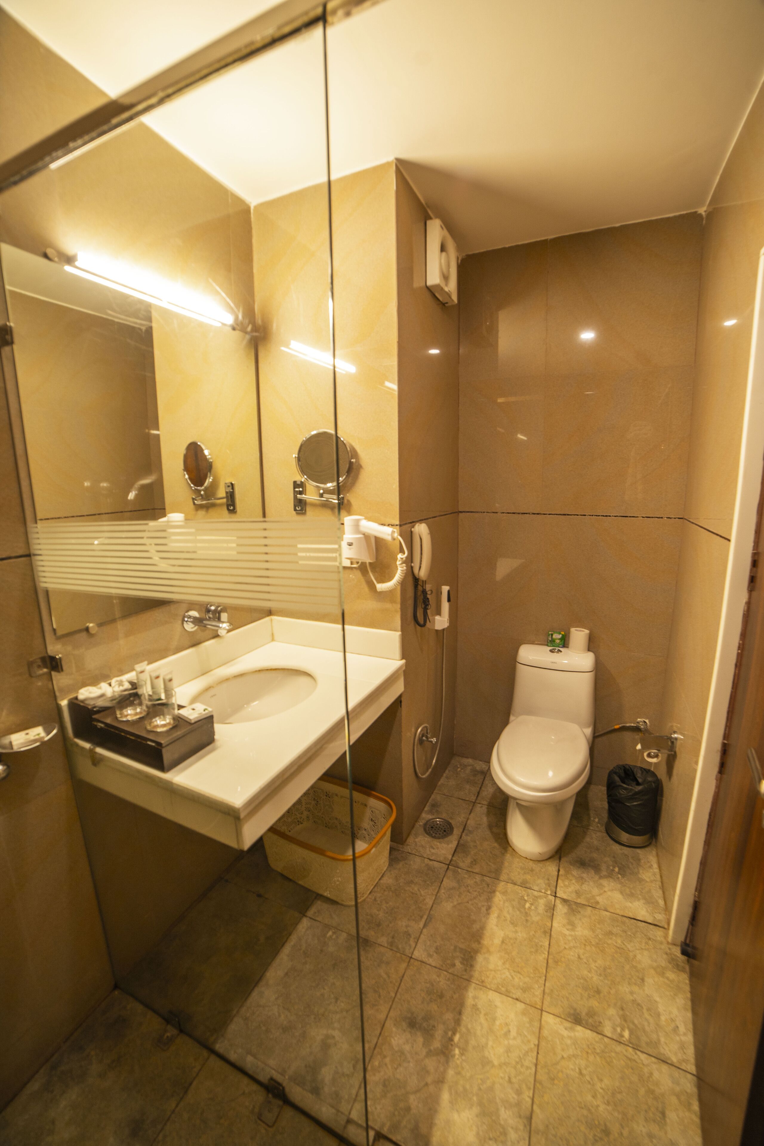 A bathroom with a glass-enclosed shower, a sink with a mirror, and a toilet.