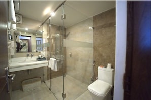 A modern bathroom with a glass shower enclosure, a white sink, and a toilet. - Hotel JSR Continental (Dehradun)