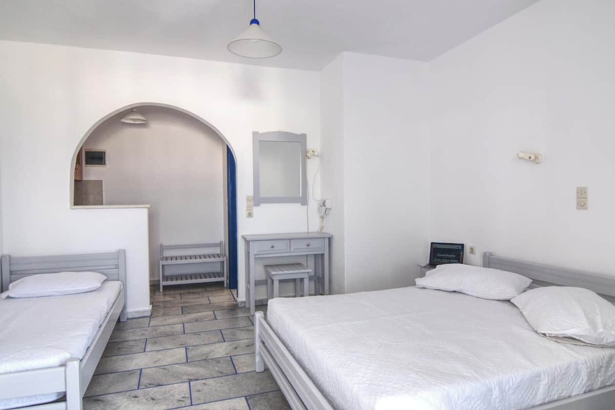 A bedroom with two single beds, a desk, a mirror, and a wardrobe.