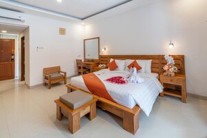 Quarto de hotel moderno com cama de madeira, mesa de cabeceira, escrivaninha e uma cadeira.