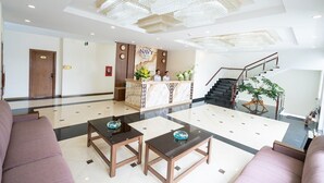A hotel lobby with a reception desk, a staircase, and a seating area with two tables. - Navy Hotel Da Lat (Lam Vien - Da Lat)