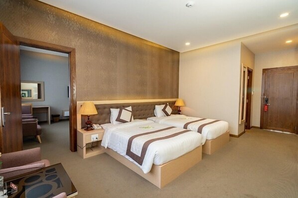 A hotel room with two beds, a desk, and a chair.