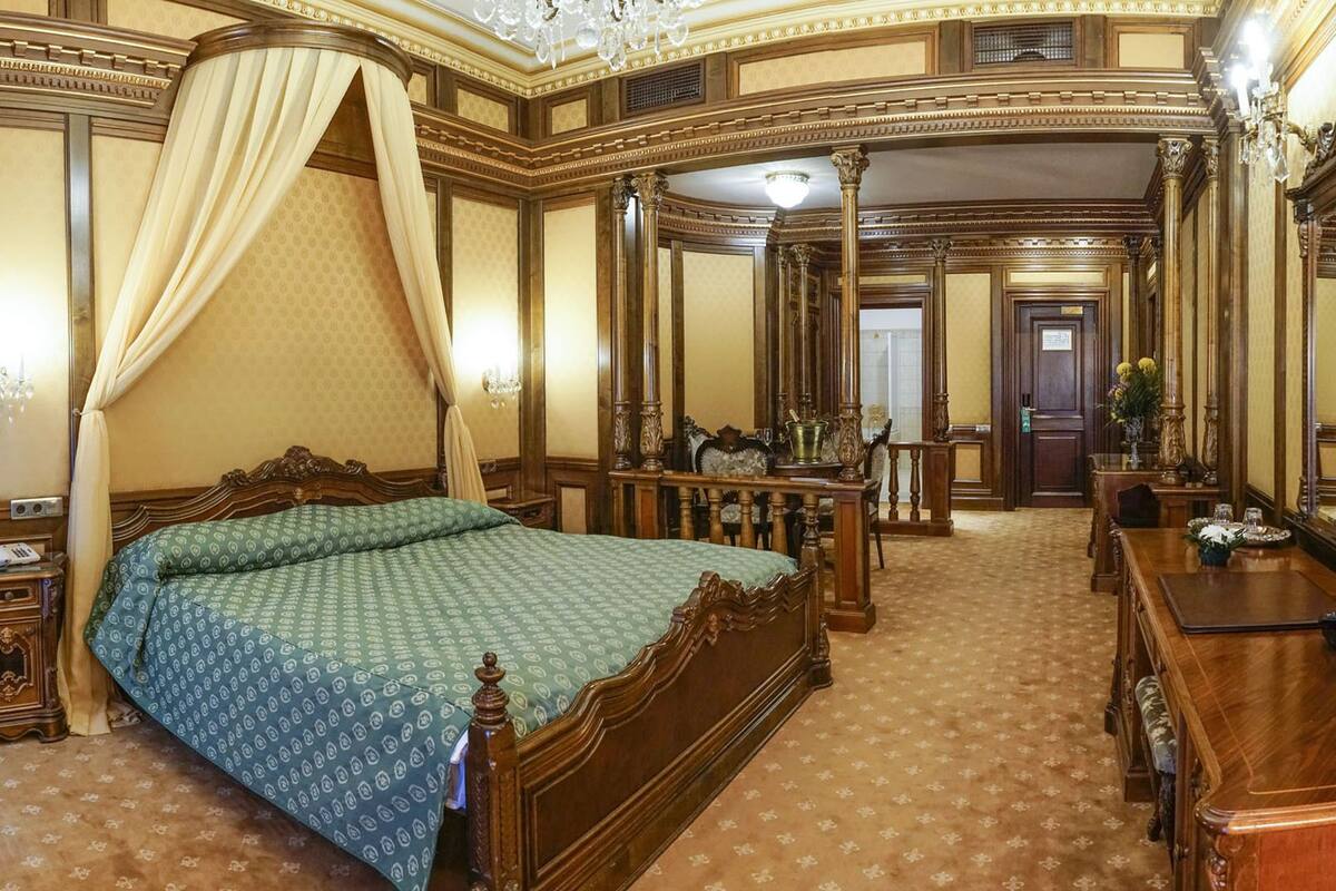 A spacious bedroom with a large bed, a vanity with a mirror, and a chandelier.