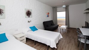 Une chambre d’hôtel avec un lit, un canapé, une petite table et une vue sur la plage.