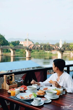 A dining table with various breakfast items and a person eating. - River Kwai View Hotel (Kanchanaburi)