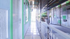 A corridor with a tiled floor, green-painted walls, and a metal railing. - OYO 1755 De'balcon Accomodation Near Ngurah Rai Airport (Kuta)