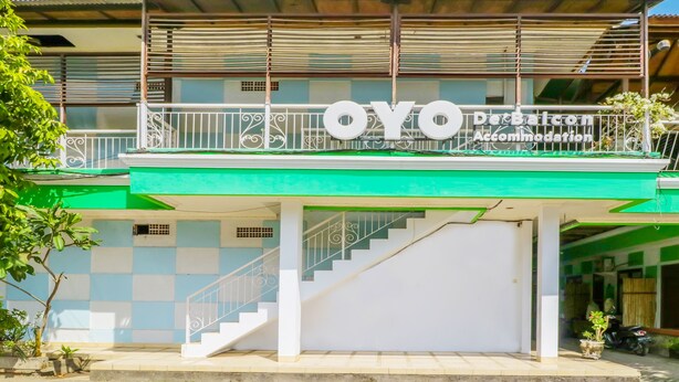 A building with a green and white facade, a balcony with a railing, and a staircase leading to the entrance. - OYO 1755 De'balcon Accomodation Near Ngurah Rai Airport (Kuta)
