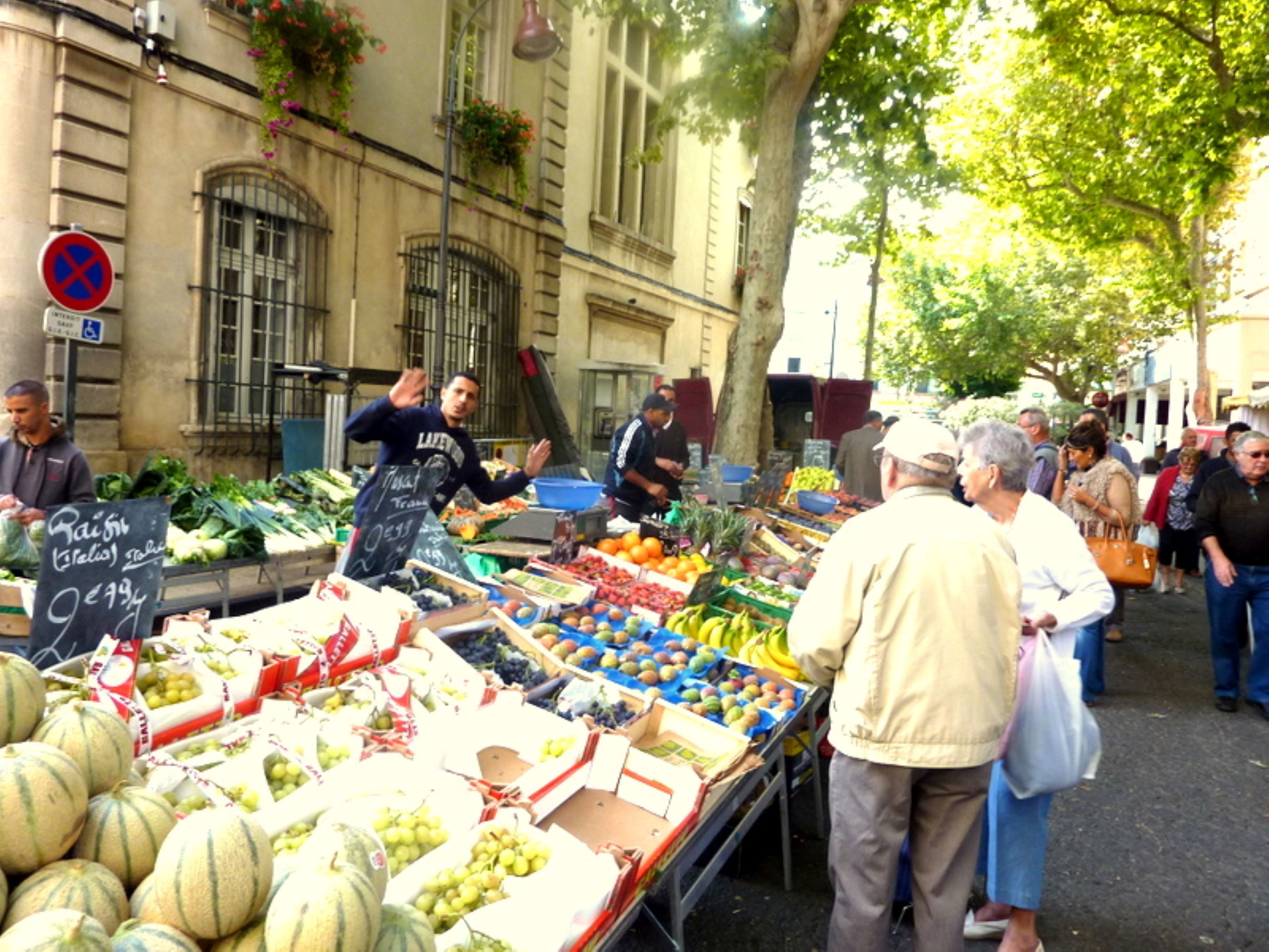 A bustling outdoor market with various fresh produce stalls.