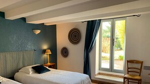 A hotel room with two beds, a window with curtains, a wall-mounted lamp, and a chair. - Bastide Sainte Agnes (Carpentras)