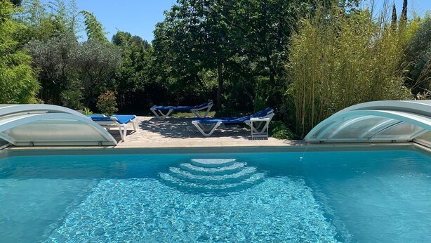 A swimming pool with clear blue water, surrounded by lounge chairs and umbrellas. - Bastide Sainte Agnes (Carpentras)
