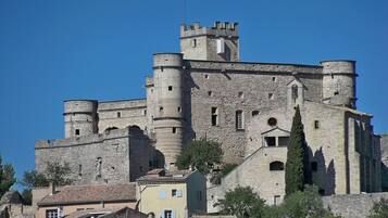 A historic stone castle with multiple towers and a fortified wall, surrounded by traditional buildings.