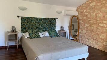 A bedroom with a bed, a nightstand, a mirror, and a wall with a stone pattern.