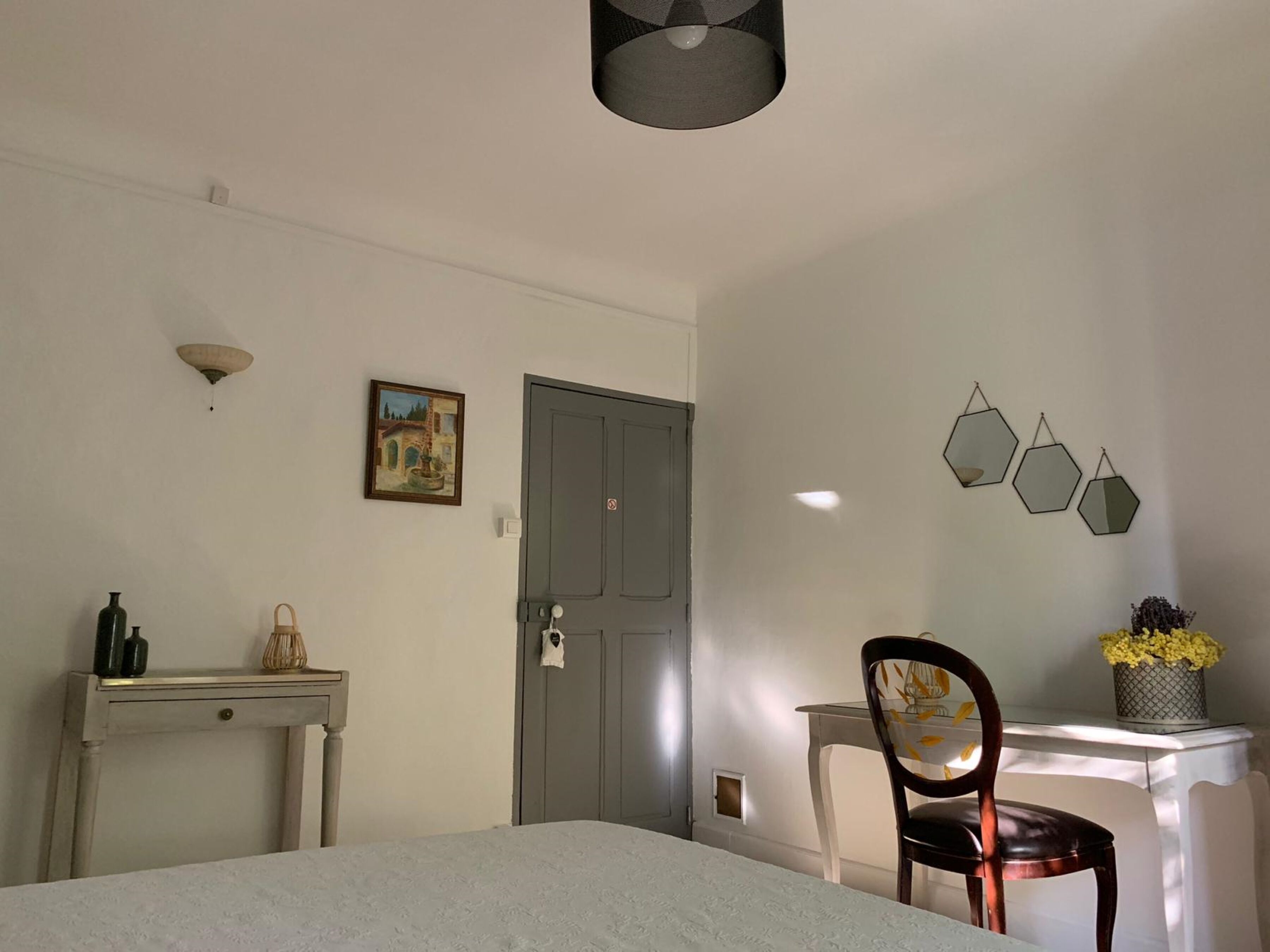 Una habitación con cama, escritorio, silla, puerta y adornos en la pared.