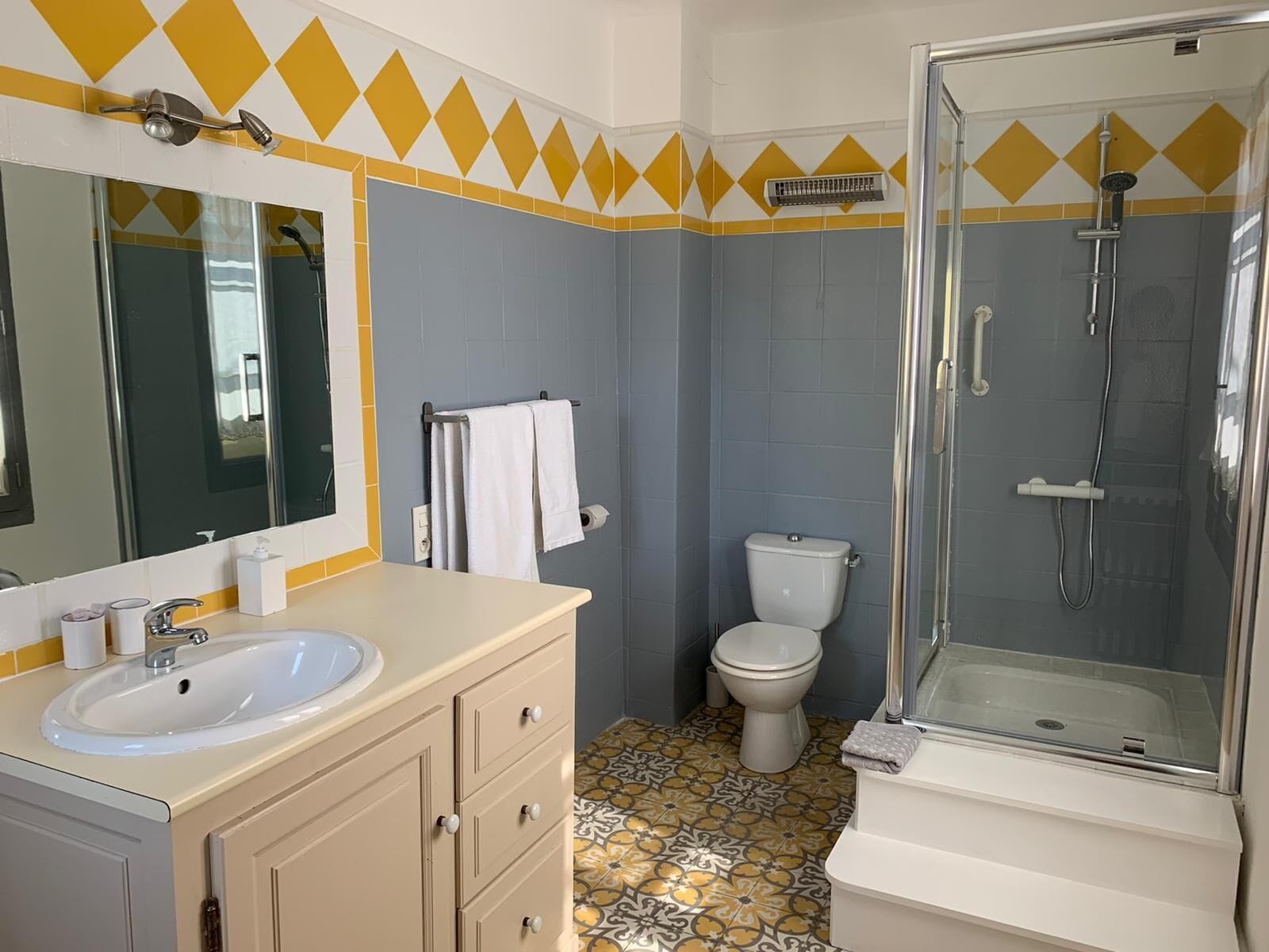 A bathroom with a sink, mirror, toilet, and shower.