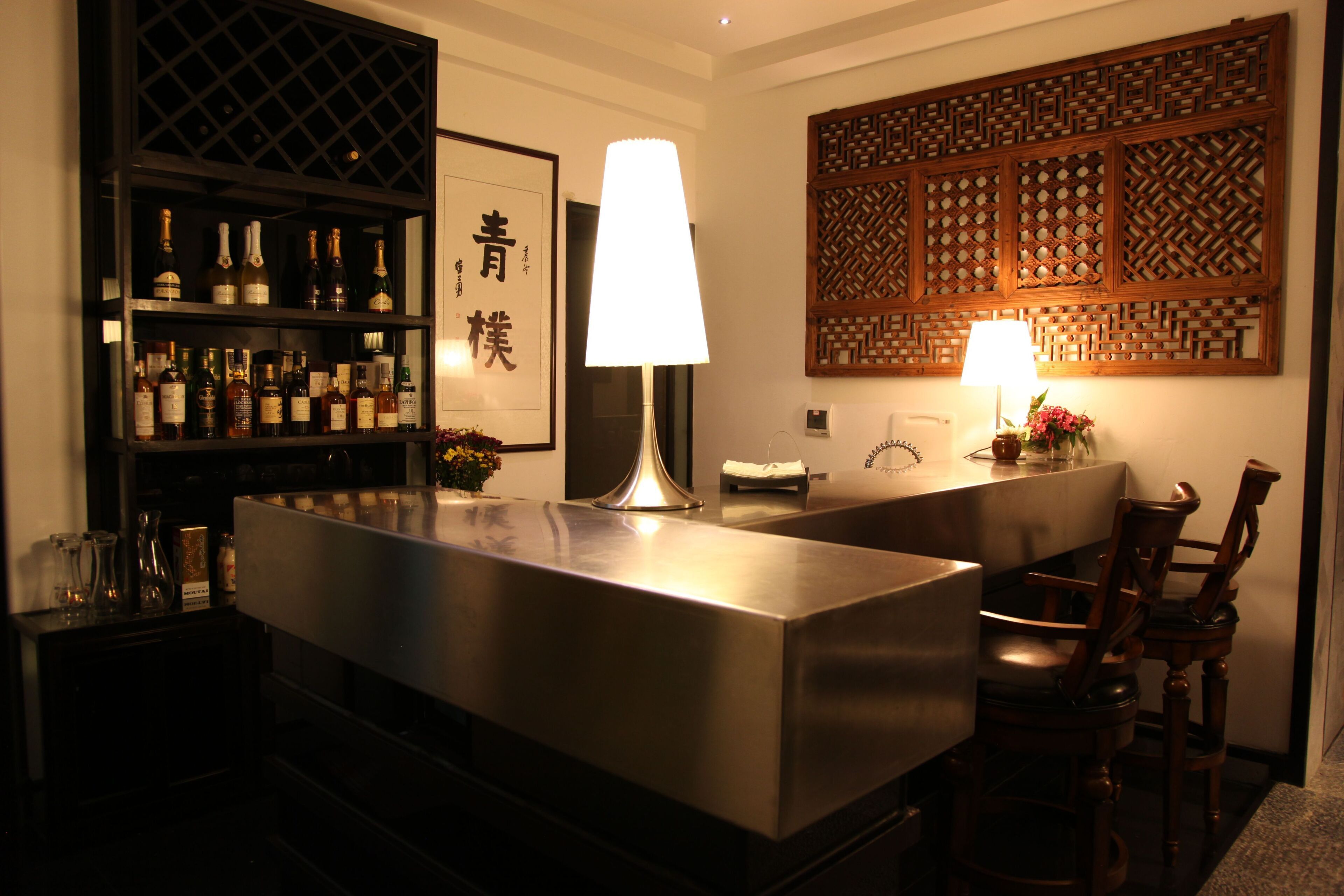 Una zona de bar con una estantería para vinos, una lámpara grande y un panel decorativo.