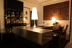 Una zona de bar con una estantería para vinos, una lámpara grande y un panel decorativo.