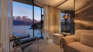 Une chambre moderne dotée d’une grande fenêtre donnant sur un plan d’eau et un pont, ainsi que d’un canapé, d’une petite table et d’un banc.