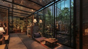 Un intérieur moderne avec de grandes fenêtres en verre, des meubles en bois et un éclairage d’ambiance.