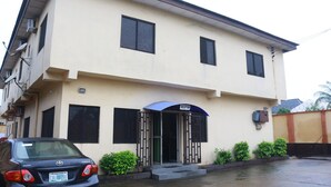 A two-story building with a reception area, a car parked in front, and a gated entrance.