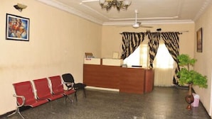 A reception area with a wooden desk, a red bench, and a ceiling fan.