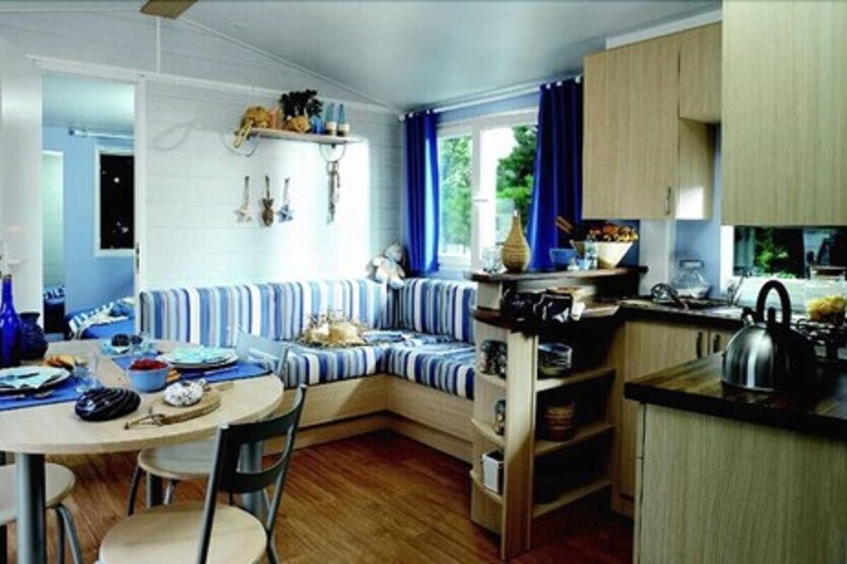 Una cocina compacta con una zona de estar integrada, una mesa de comedor y una ventana con cortinas.