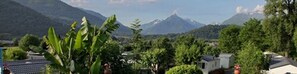 A residential area with houses, lush greenery, and mountains in the background.
