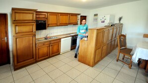 A kitchen with wooden cabinets, a dishwasher, and a refrigerator. - Baka Ljuba (Kutjevo)