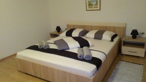 A neatly made bed with striped bedding and rolled towels, a bedside table with a lamp, and a small rug on the floor. - Baka Ljuba (Kutjevo)