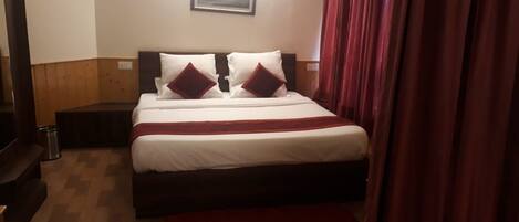 A neatly made bed with white and red bedding, a wooden headboard, and a small bedside table with a lamp.