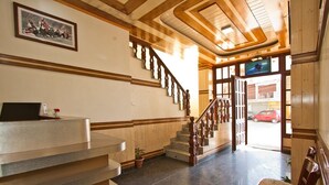 Un hall de hotel con una recepción, una escalera y vistas a la calle.