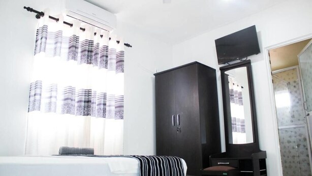 Un dormitorio con cama, armario, televisor y zona de ducha.