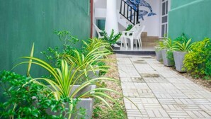 Un sendero bordeado por macetas con plantas que conduce a un edificio con un mural de ballenas y el texto 'FUN WHALES'.