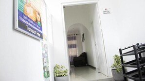 Un pasillo con un cartel que indica transporte gratuito, una silla negra y un letrero en la pared que dice 'Deje sus zapatos aquí'.
