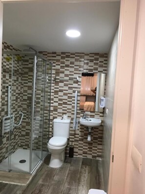 A bathroom with a glass shower enclosure, a toilet, and a sink.