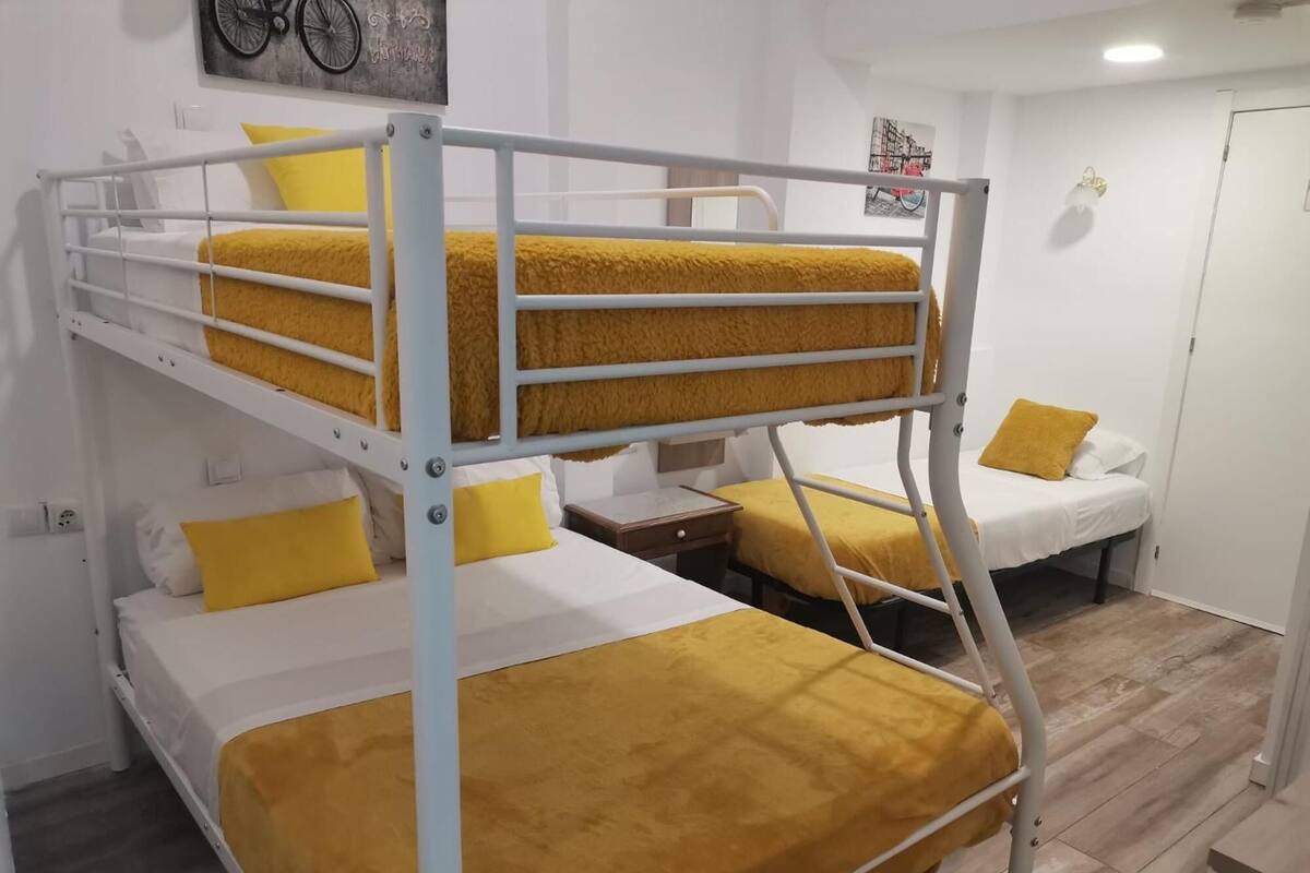 Une chambre avec un lit superposé, comportant deux lits, chacun avec une couverture et un oreiller jaunes.