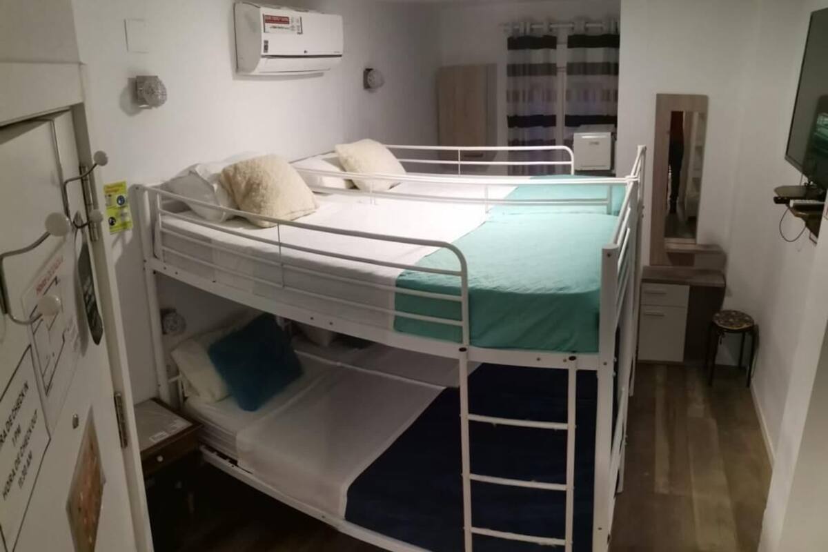 Une chambre avec un lit superposé, un bureau, un miroir et une télévision.